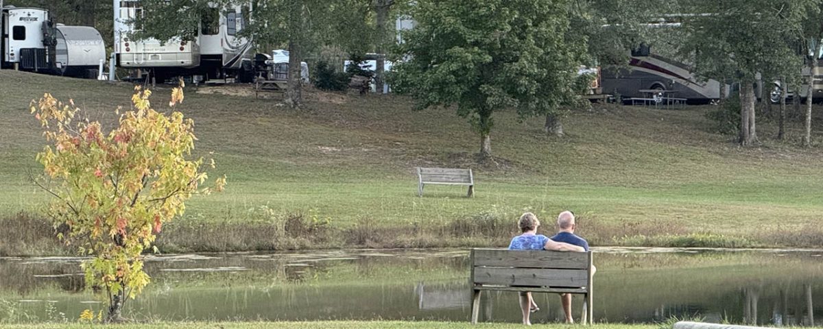 Couple relaxing beside the pond during spring at Deer Run RV Park in Troy, Alabama