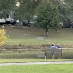 Couple relaxing beside the pond during spring at Deer Run RV Park in Troy, Alabama
