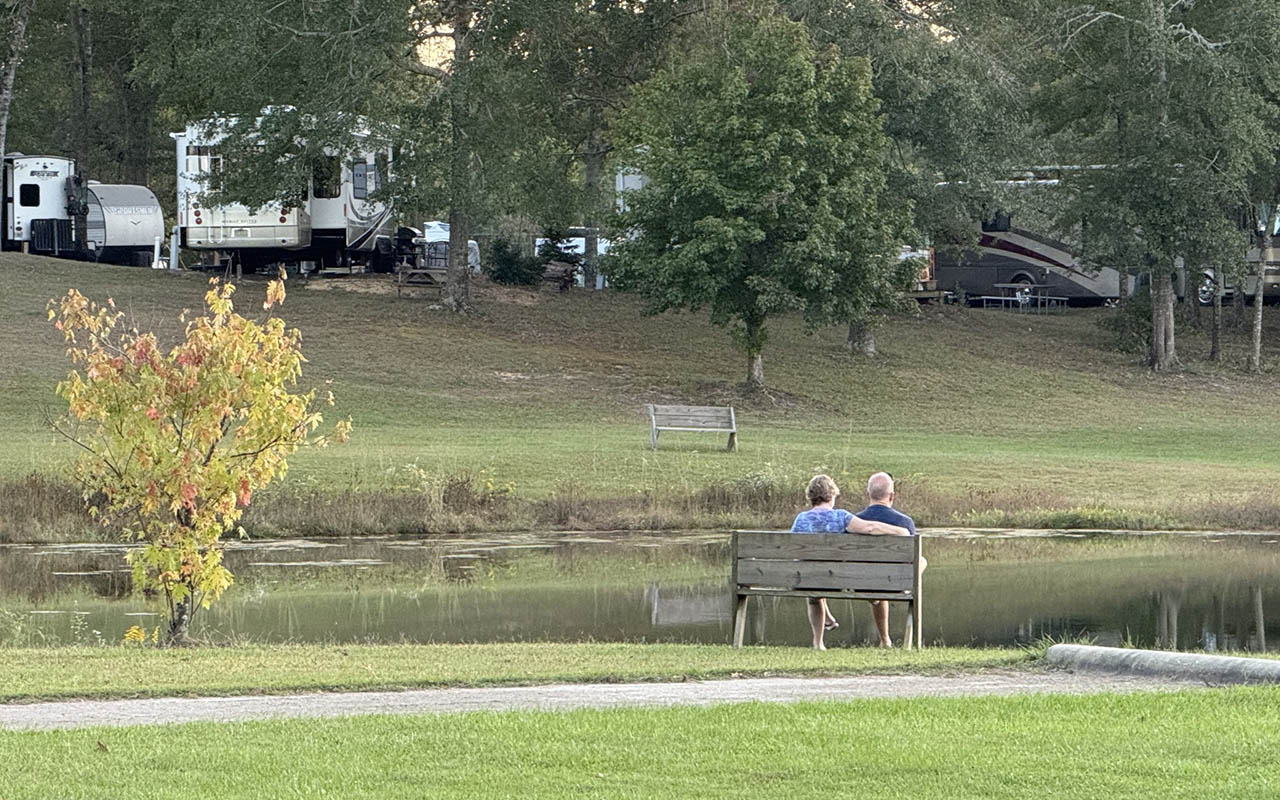 Couple relaxing beside the pond during spring at Deer Run RV Park in Troy, Alabama